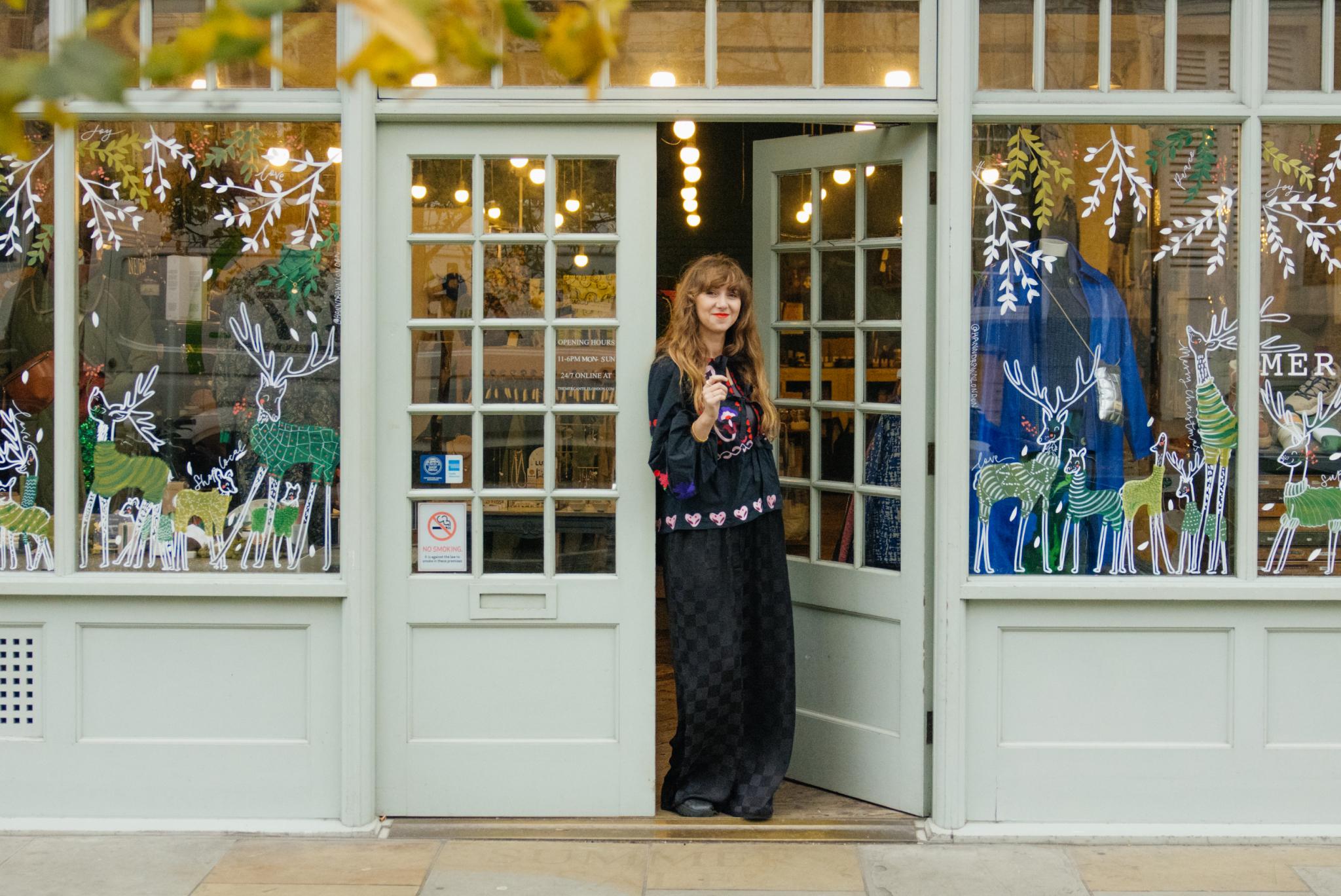 a shopkeeper stands in the doorway of her shop