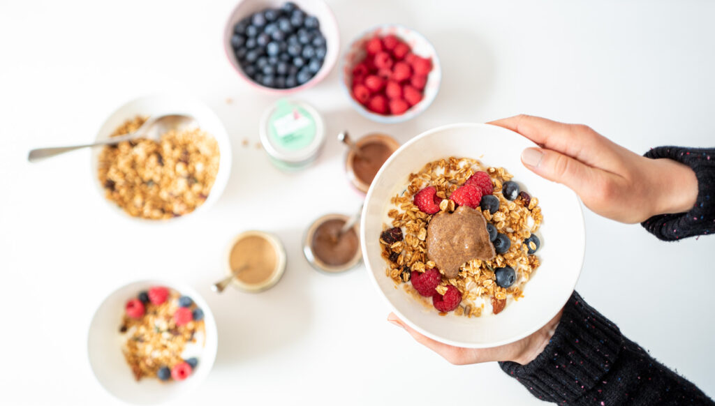 Eine weisse Schüssel von Muesli mit Himbeere und Blaubeere ist ein Beispiel von Bio Produkte verkaufen.