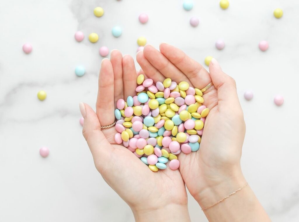 Des mains tenant des bonbons colorés lors de l'ouverture d'un magasin de bonbons