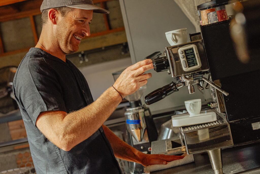 Barista souriant préparant un café fraîchement moulu pour l'ouverture de son café-boutique